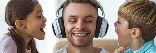 Preview: The happy father in headphones playing with a boy and a girl at the desk.