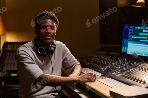 Preview: Young Adult Black Man Working at Audio Mixing Console in Recording Studio