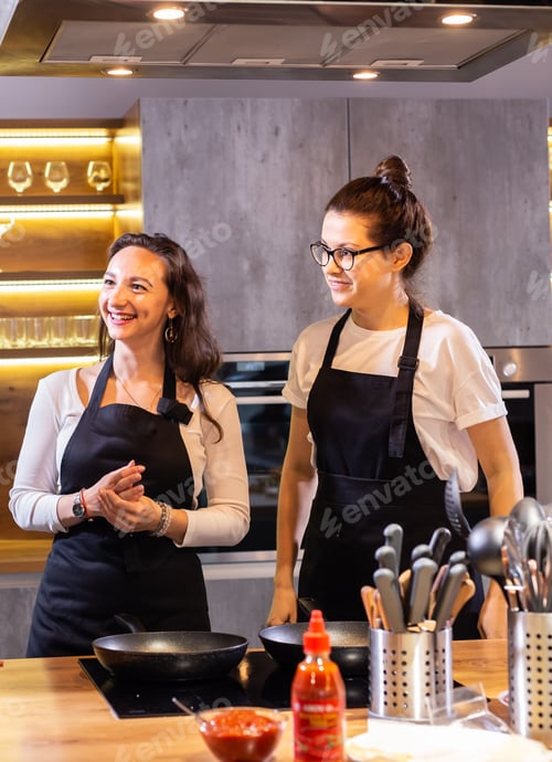 Preview: Two funny professional female chefs laughing and cooking food in large kitchen
