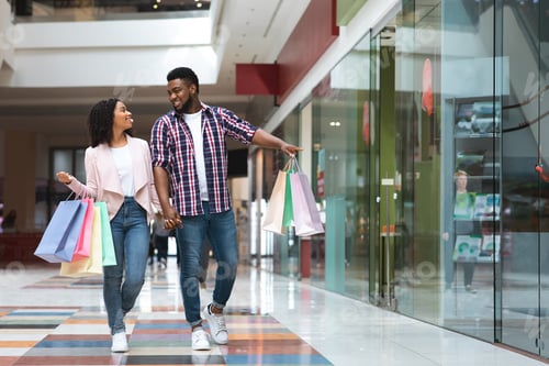 Preview: Black Friday Sales. Happy African Couple Walking With Shopping Bags In Mall