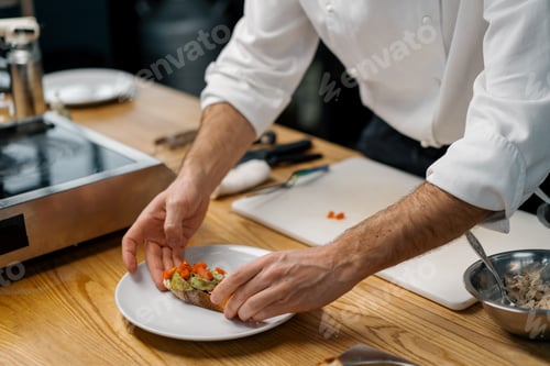 Preview: A professional chef puts roasted avocado and tomatoes on toast with spices pouring sauce over them