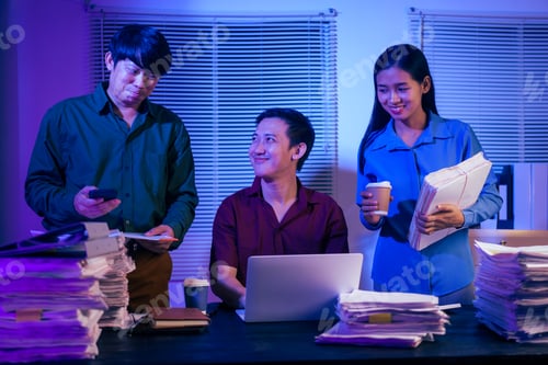 Preview: Three young businessmen work together in office at night, busy on their laptops,checking documents
