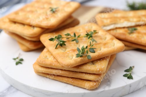 Preview: Tasty salty crackers with thyme on white table, closeup