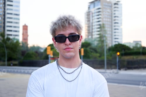 Preview: Young influencer posing in urban setting wearing sunglasses and silver chains