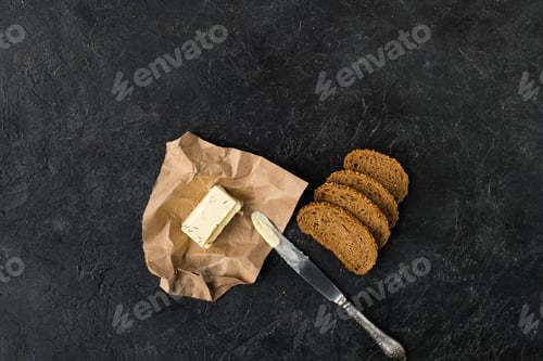 Preview: top view of slices of bread, butter rand knife on dark tabletop