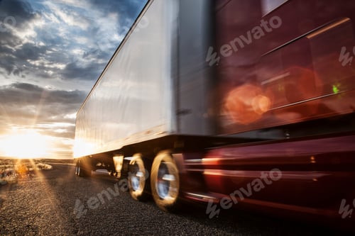Preview: Low angle view of the cab and trailer on a Class 8 commercial truck on the highway at sunset.