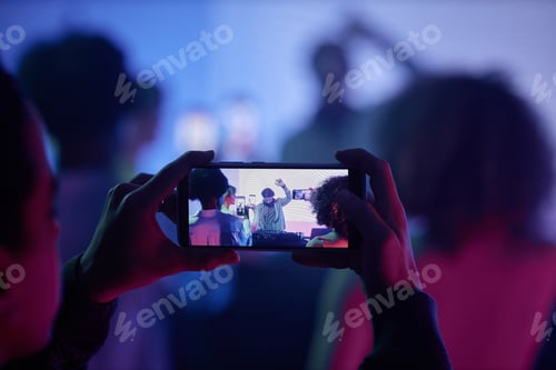 Preview: Closeup of man filming DJ at disco party via smartphone