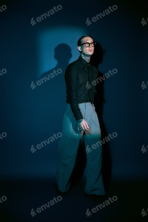 Preview: Stylish young man exudes confidence with modern flair in a striking dark setting