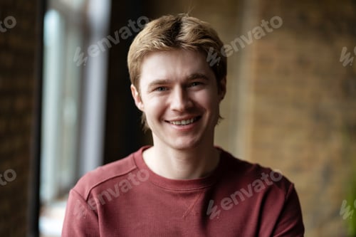 Preview: Portrait of smiling young man with blond hair wearing red sweatshirt