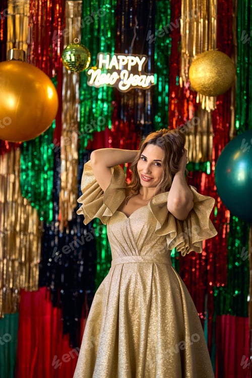 Preview: beautiful woman in luxurious golden dress posing beside a Christmas tree