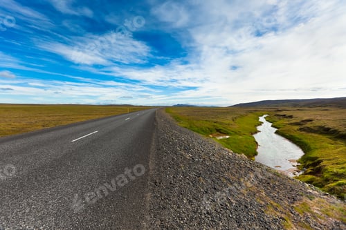 Preview: Highway through Icelandic landscape under a blue summer sky with clouds