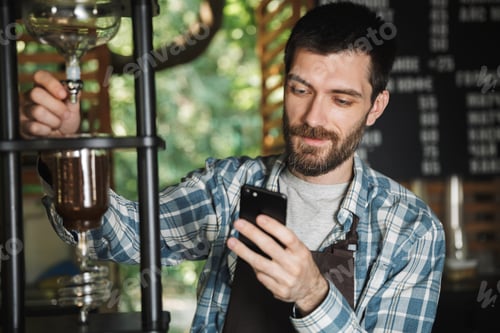 Man Brewing Coffee While Looking at Phone