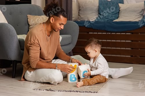 Preview: Young father and little son playing cubes on the floor of the room