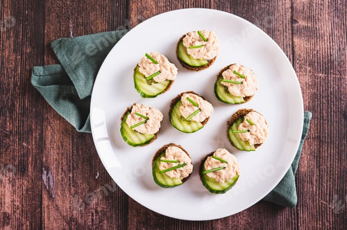 Preview: Close up of delicious sandwiches on rye bread with cucumber, capelin caviar and onions top view