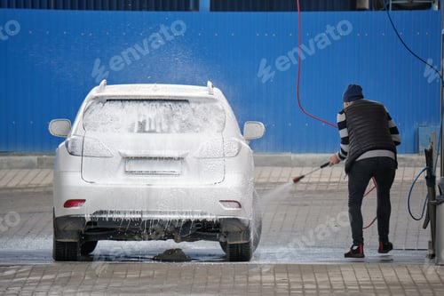 Preview: Closeup of male driver washing his car with contactless high pressure water jet