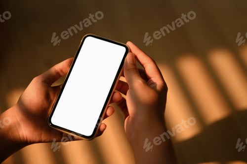 Preview: Woman holding smartphone with blank screen sitting in living room. Closeup