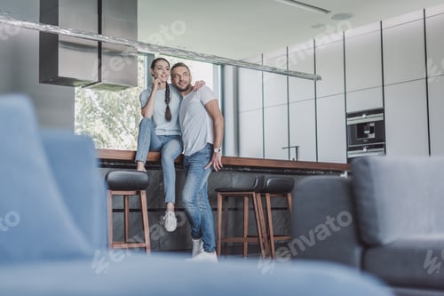 Aperçu: selective focus of attractive woman sitting on kitchen counter and embracing boyfriend at home