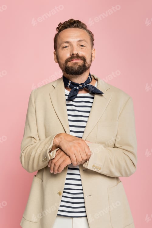 Preview: pleased french man in blazer and neck scarf looking at camera isolated on pink