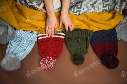 Preview: Cropped image of woman choosing winter hat on brown