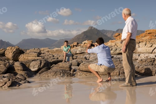 Preview: Father clicking photo of his son with mobile phone on beach in the sunshine