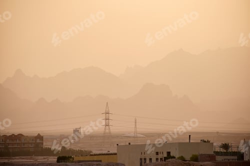 Preview: Sunset landscape with remote hotel complex against dark mountain peaks in egyptian desert
