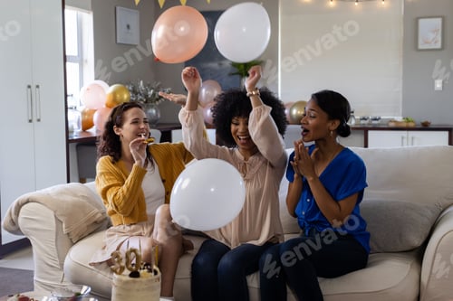 Preview: Women celebrating with balloons on couch, enjoying party atmosphere at home