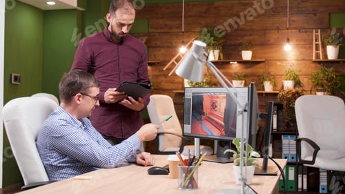 Preview: Graphic designer working in gaming industry showing new virtual game design to his colleague