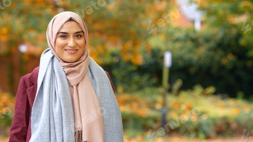 Preview: Head And Shoulders Portrait Of Smiling Young British Muslim Woman Wearing Hijab In Autumn Park