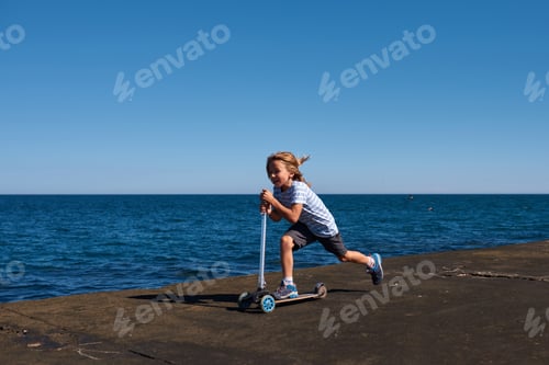 Preview: Boy riding a scooter on a pier at sunny day