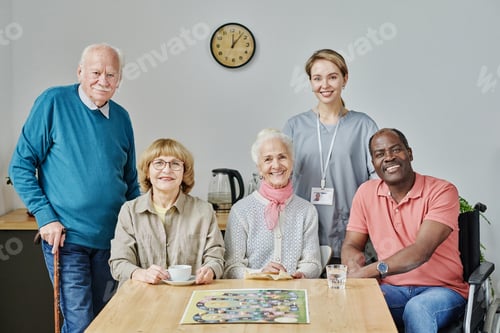 Preview: Senior people with caregiver playing board game