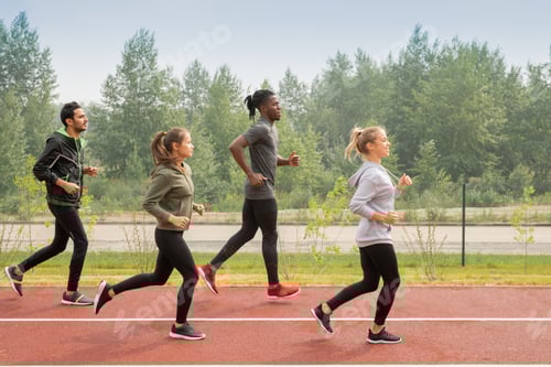Vista previa: Vista lateral de cuatro jóvenes deportistas corriendo por los hipódromos