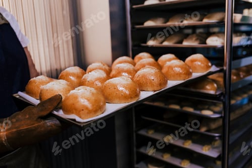 Preview: close up view of woman holding holding rack of rolls in a bakery.
