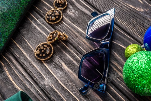 Preview: close up view of stylish sunglasses and earrings on wooden tabletop