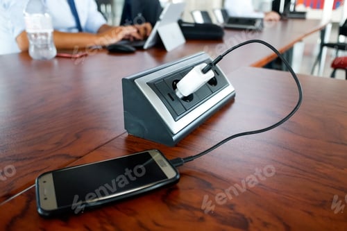 Preview: A mobile phone is charge into a socket on a table in a European work office.