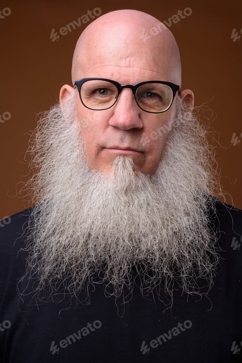 Preview: Mature bald man with long gray beard against brown background