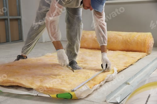 Preview: Worker measuring and cutting insulation material indoors
