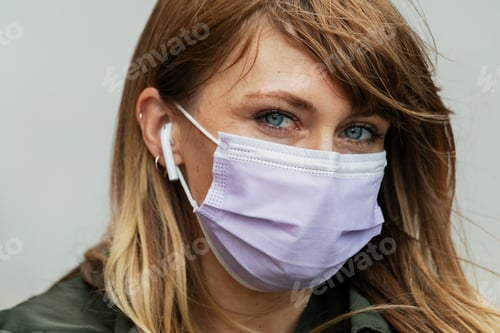 Preview: Woman in a face mask listening to music during coronavirus pandemic