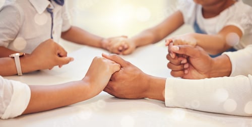 Preview: Close up of family holding hands in prayer while sitting at table. Parents and children saying grac