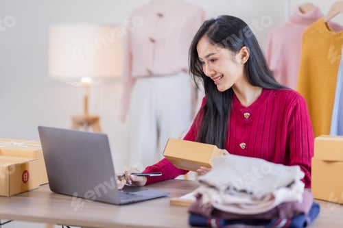 Preview: Asian women SME selling clothes online, She is answering customers' questions by phone and laptop