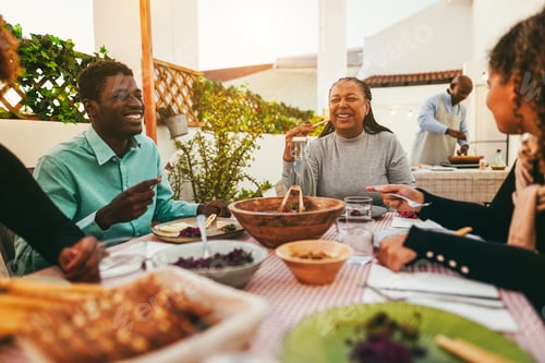 Preview: Happy african family eating lunch together at home terrace outdoor - Focus on senior woman face