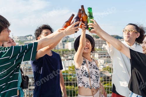 Preview: Group of young Japanese men and women standing on a rooftop in an urban setting, drinking beer.