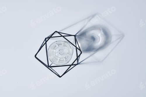 Preview: Flatlay of metal wire handmade holder with glass of water inside and its shadow