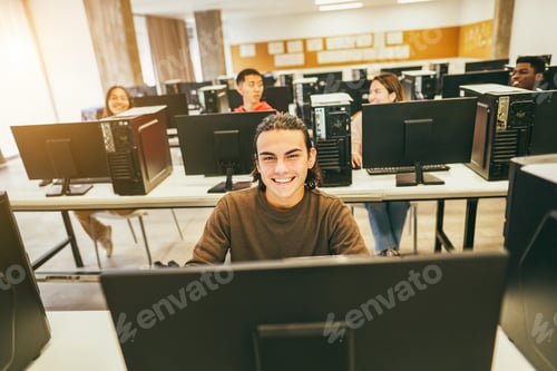 Preview: Young students using computers inside technology class at school room - Focus on center guy face