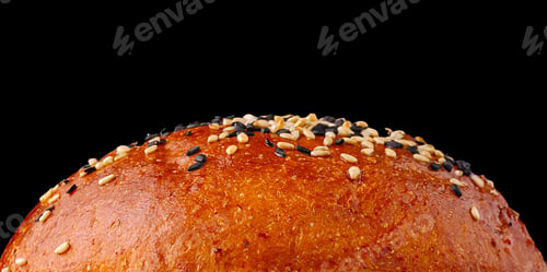 Preview: Freshly baked sesame seed bun with glossy finish on a black background