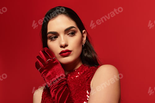 Preview: Elegant young woman in a vibrant studio with striking red tones