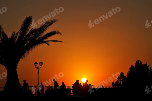 Preview: setting sun and silhouettes of people on the embankment