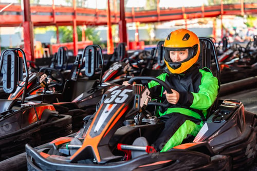 Preview: Young racer in helmet sitting in go kart