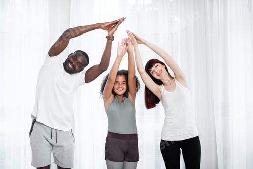 Preview: Happy cheerful pleasant multiethnic family doing sport together at home