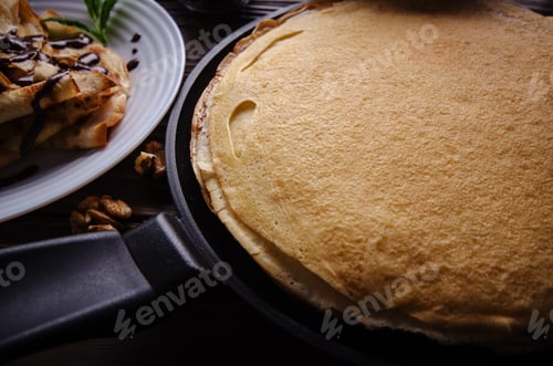 Preview: French crepes with chocolate sauce and walnuts in ceramic dish o