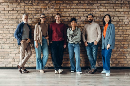Preview: Group of diverse multinational team posing by brick wall: colleagues collaboration and innovation